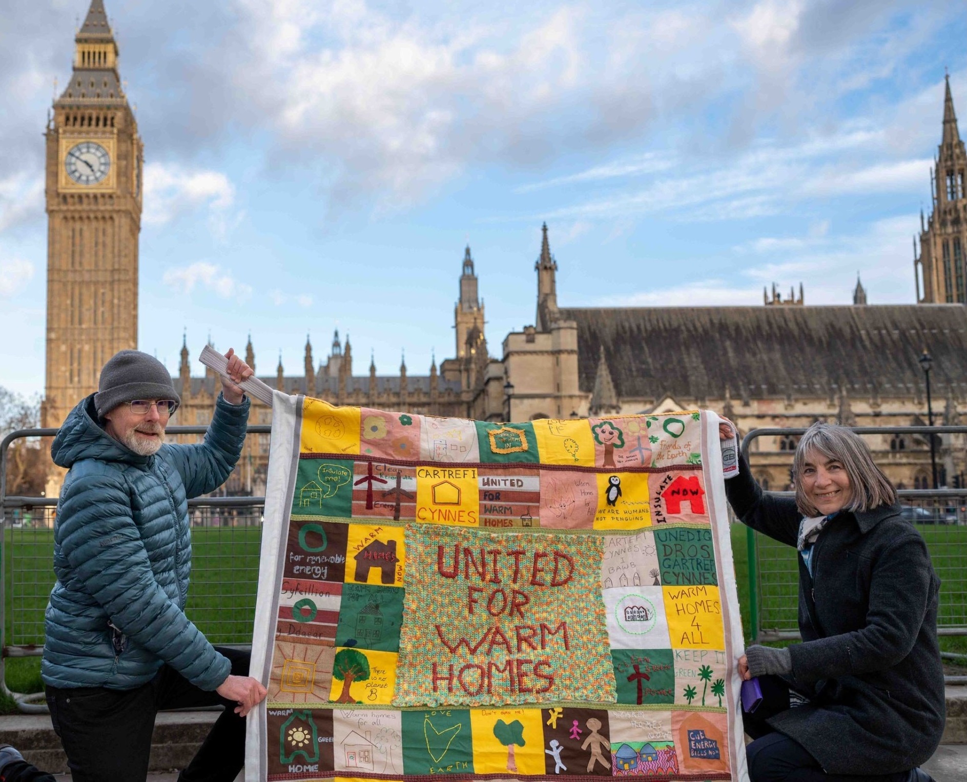 Jenny and Terry holding up their quilt outside Westminster
