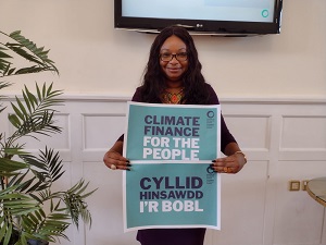 Women of colour holding up a sign saying Climate Finance in English and Welsh