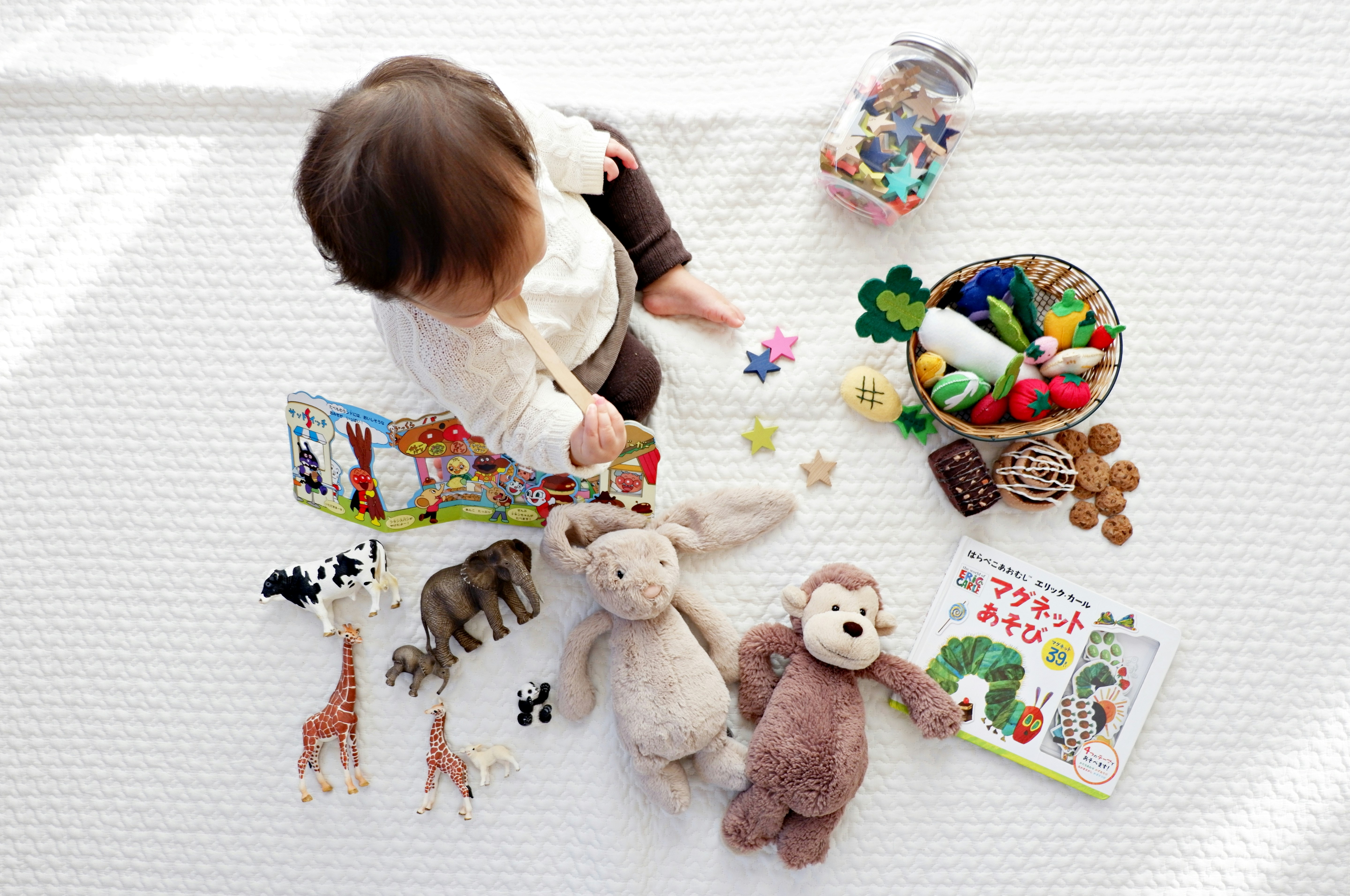 Baby on a rug surrounded by toys