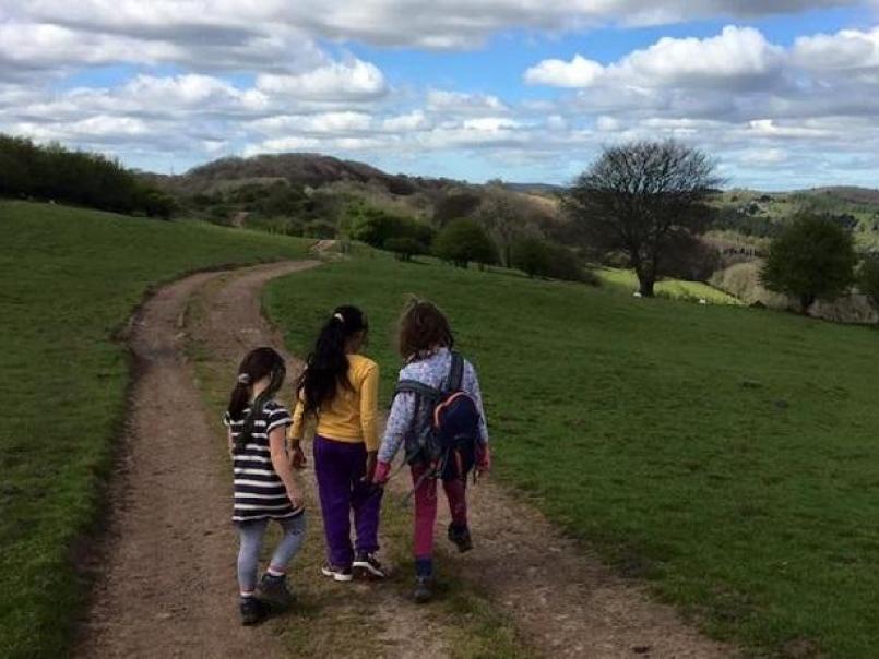 Three children walking down a countryside path with blue skies above
