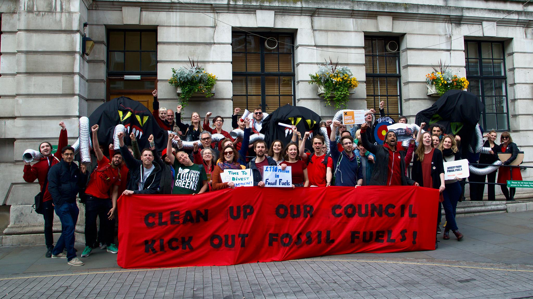 People protesting holding a banner 'Clean up our council - kick out fossil fuels'
