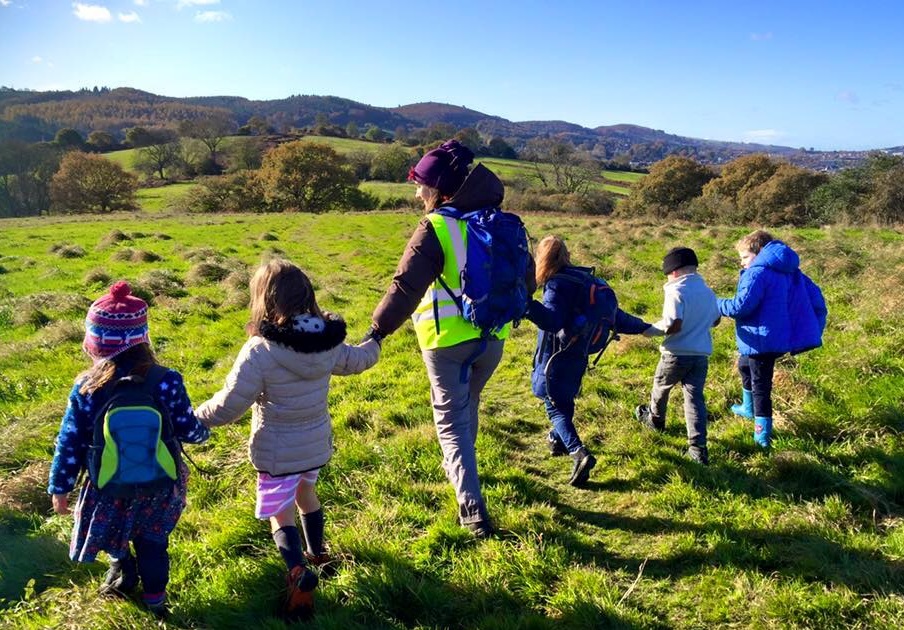 Women walking hand in hand with children in green fields
