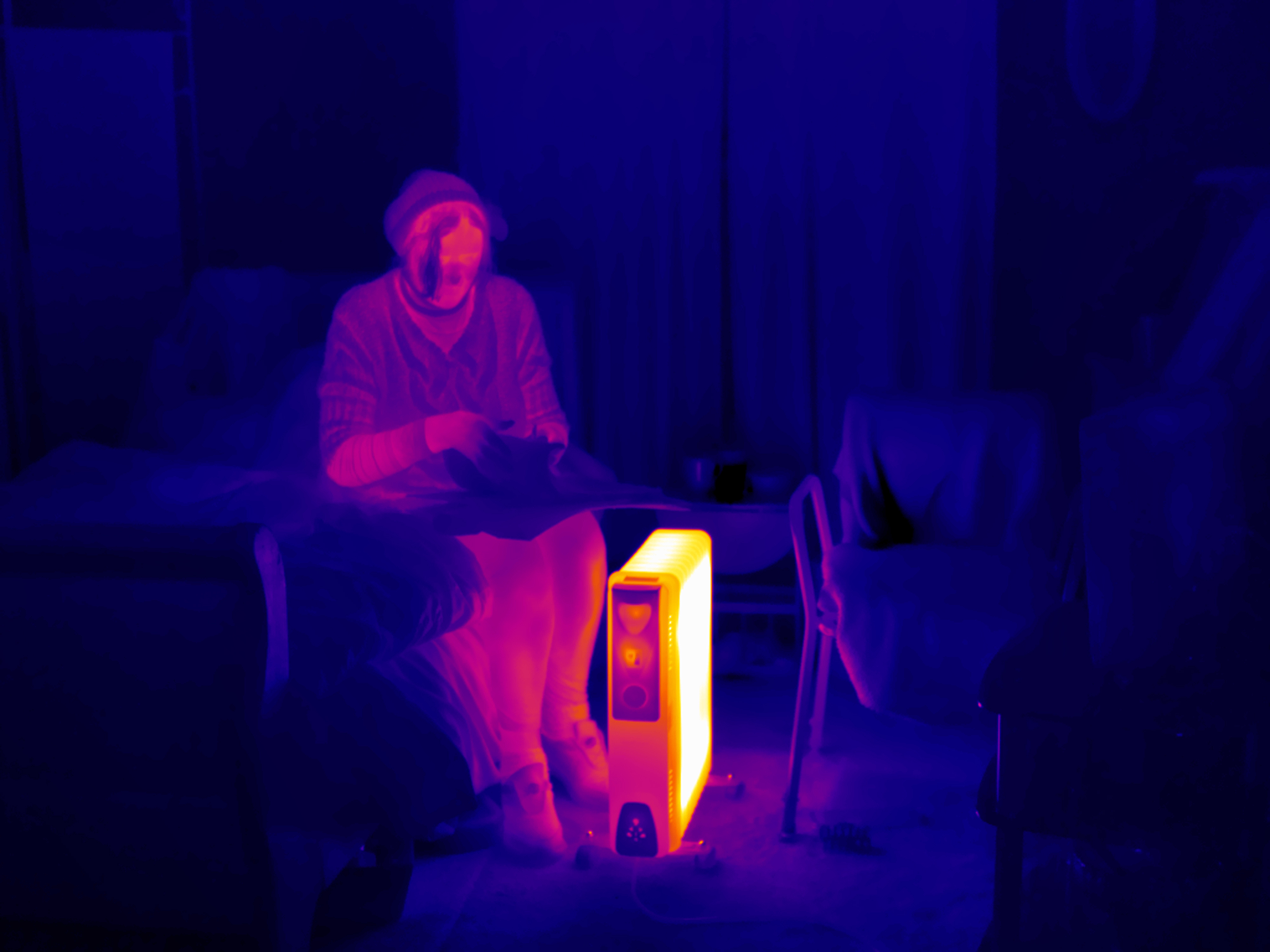 Thermal image of a woman trying to keep warm in her home