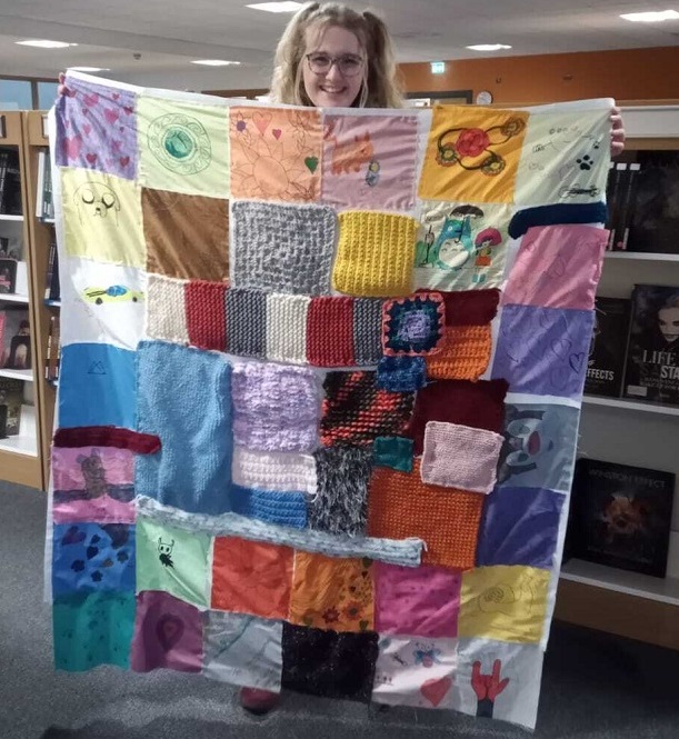 Person holding up a handmade patchwork quilt