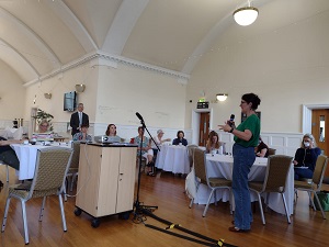 Women talking with a microphone to a room of people