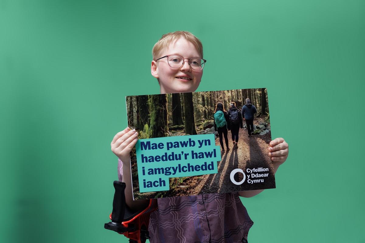 Mae merch ifanc yn dal arwydd yn dweud "Mae pawb yn haeddu'r hawl i amgylchedd iach"