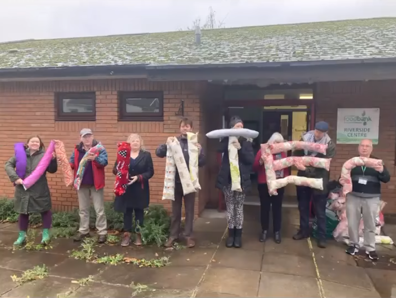 People holding draught excluders spelling out 'winter;