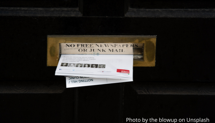Picture of a front door with junk mail pushed halfway through the letter box