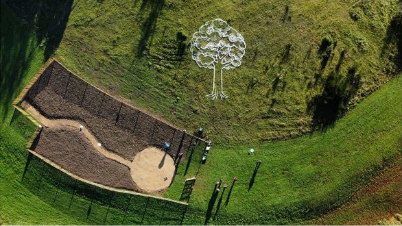 An aerial shot of Tiny Forest Caerffili at the beginning of planting week, next to a huge tree - a piece of nature art waiting to be filled in.