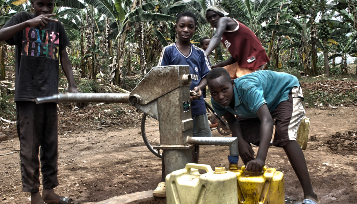 Children gathering around a water pump in an African village