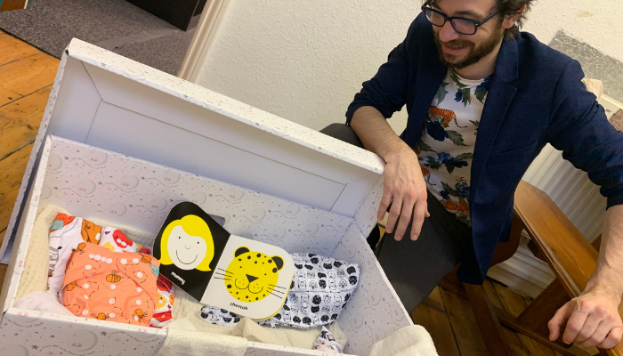 Picture of a man looking inside a sustainable baby box containing reusable nappies and other items