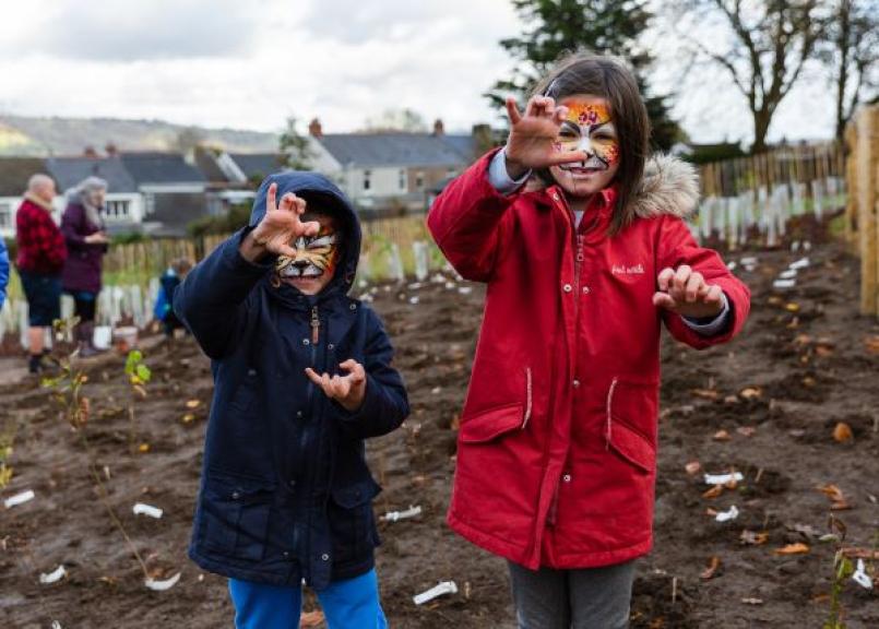 Two children with tiger faces at a tree planting event
