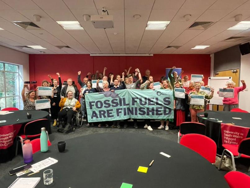 Group of people standing behind a banner, 'Fossil fuels are finished'