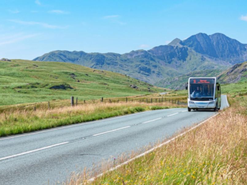 Bus on a road in rural Wales with mountains in background