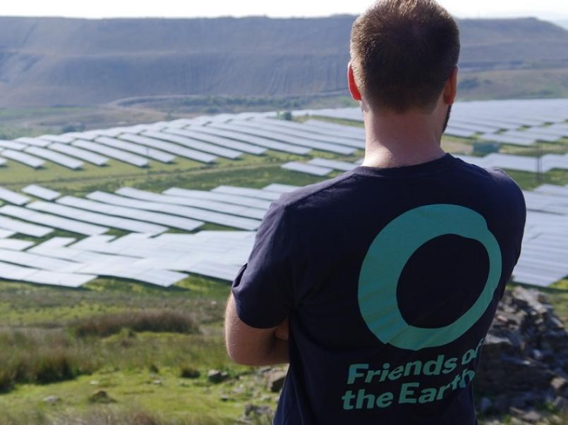 Person with FOE teeshirt looking at solar panels on a hillside