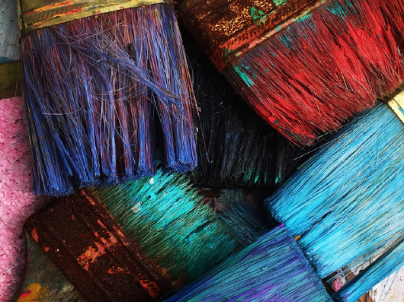 Photo of paint brushes dipped in different colour paint.