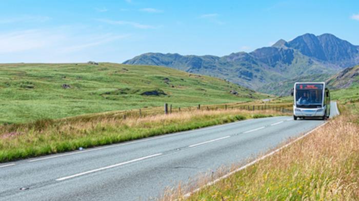 Bus on a road in rural Wales with mountains in background