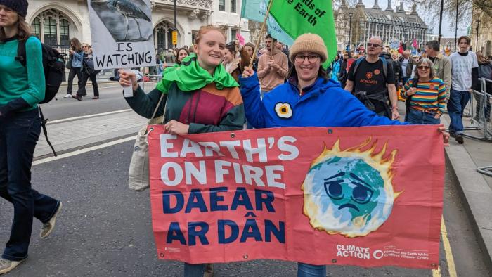 Two people at a protest holding a Earth's on Fire sign